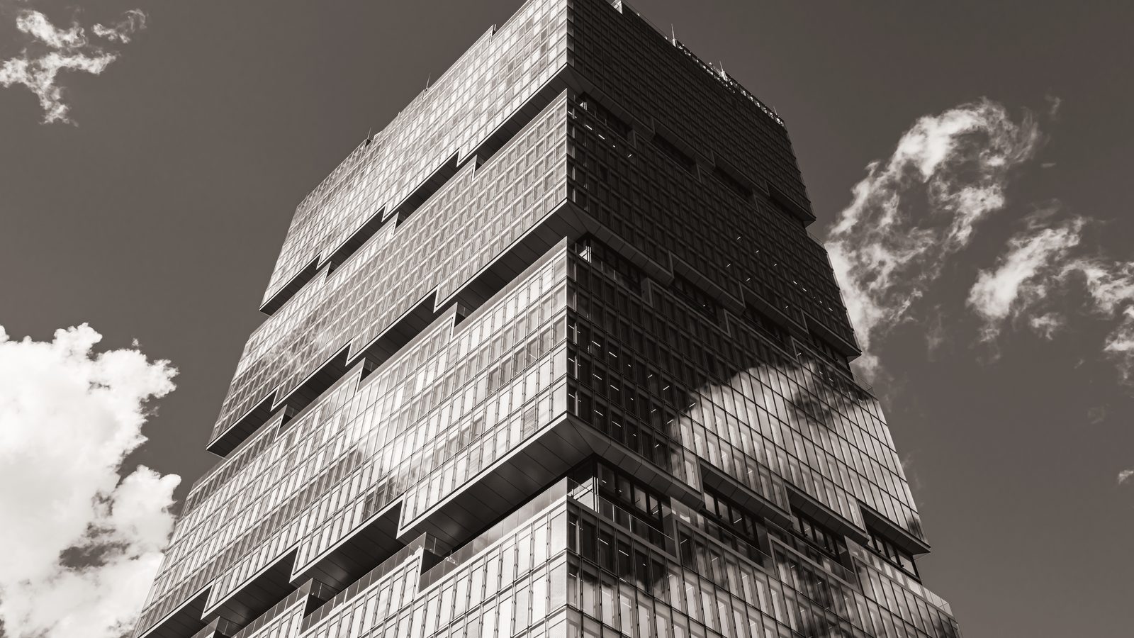 A modern glass office tower, seen from below against the sky